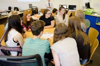 Teenagers sat around a classroom table