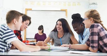 Teenagers laughing around a classroom table